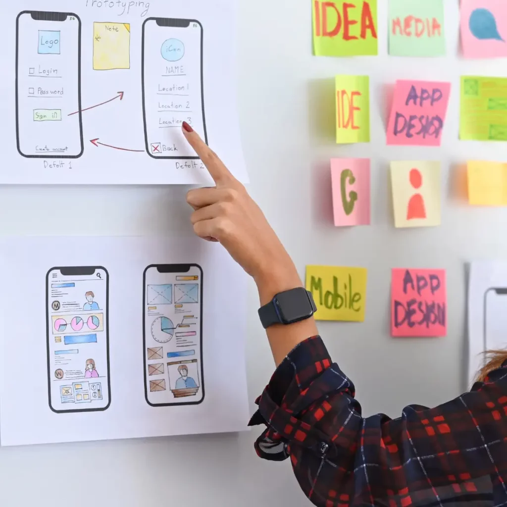 person pointing at a board with app layout designs