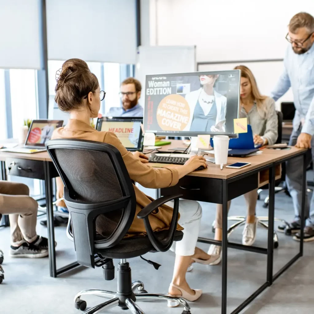 office people sat at desks working on laptops and computers