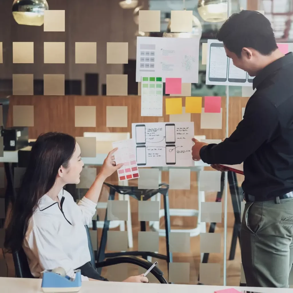 people looking at app designs and layouts stuck on a wall