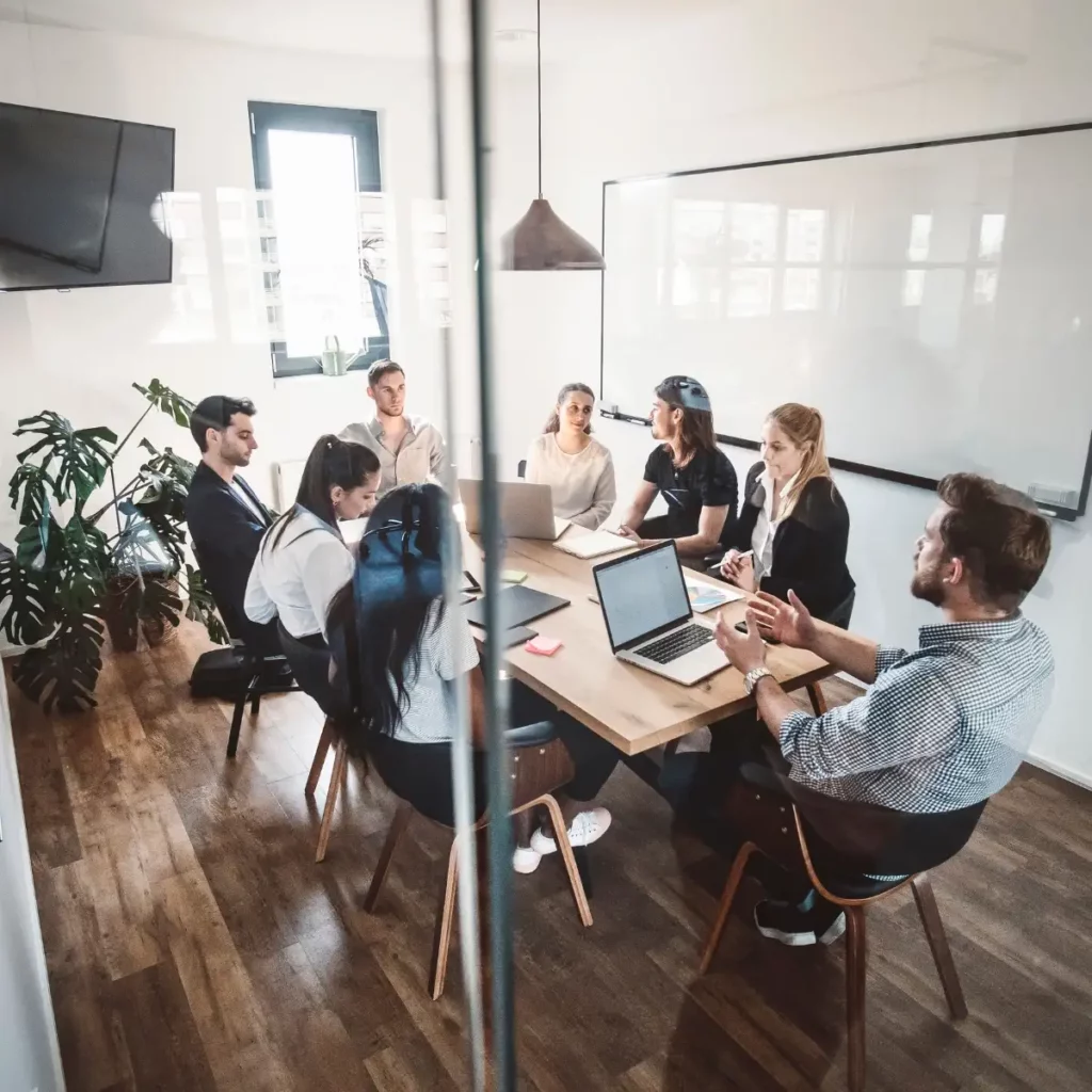 people in an office sat around a desk having a meeting