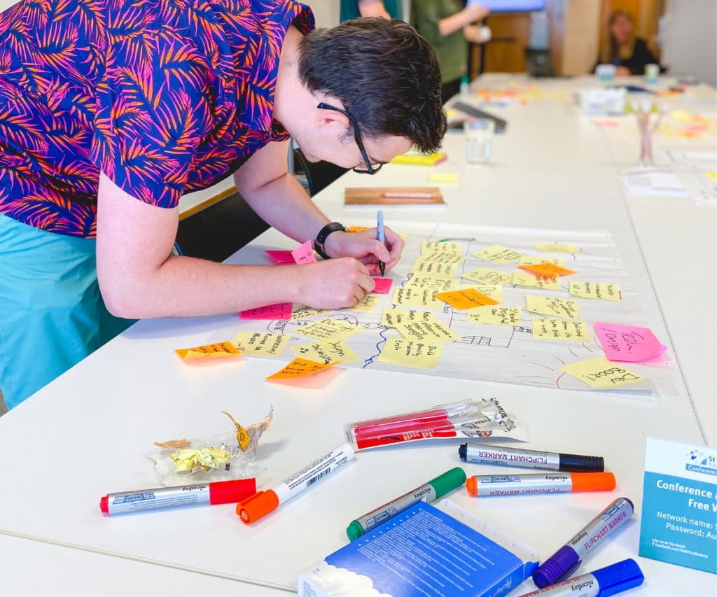 person writing on post it notes and adding to a list