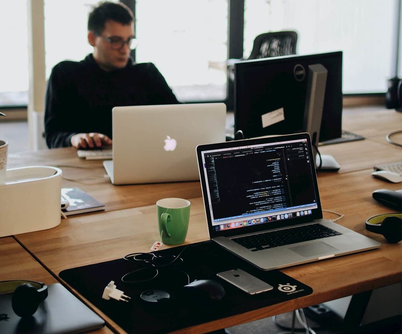 Picture of Apple laptops and out source software development taking place coding at a desk and working on a minimum viable product