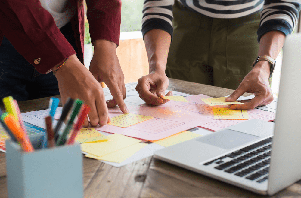 Two people working with post its as they create a Minimum Viable Product (MVP)