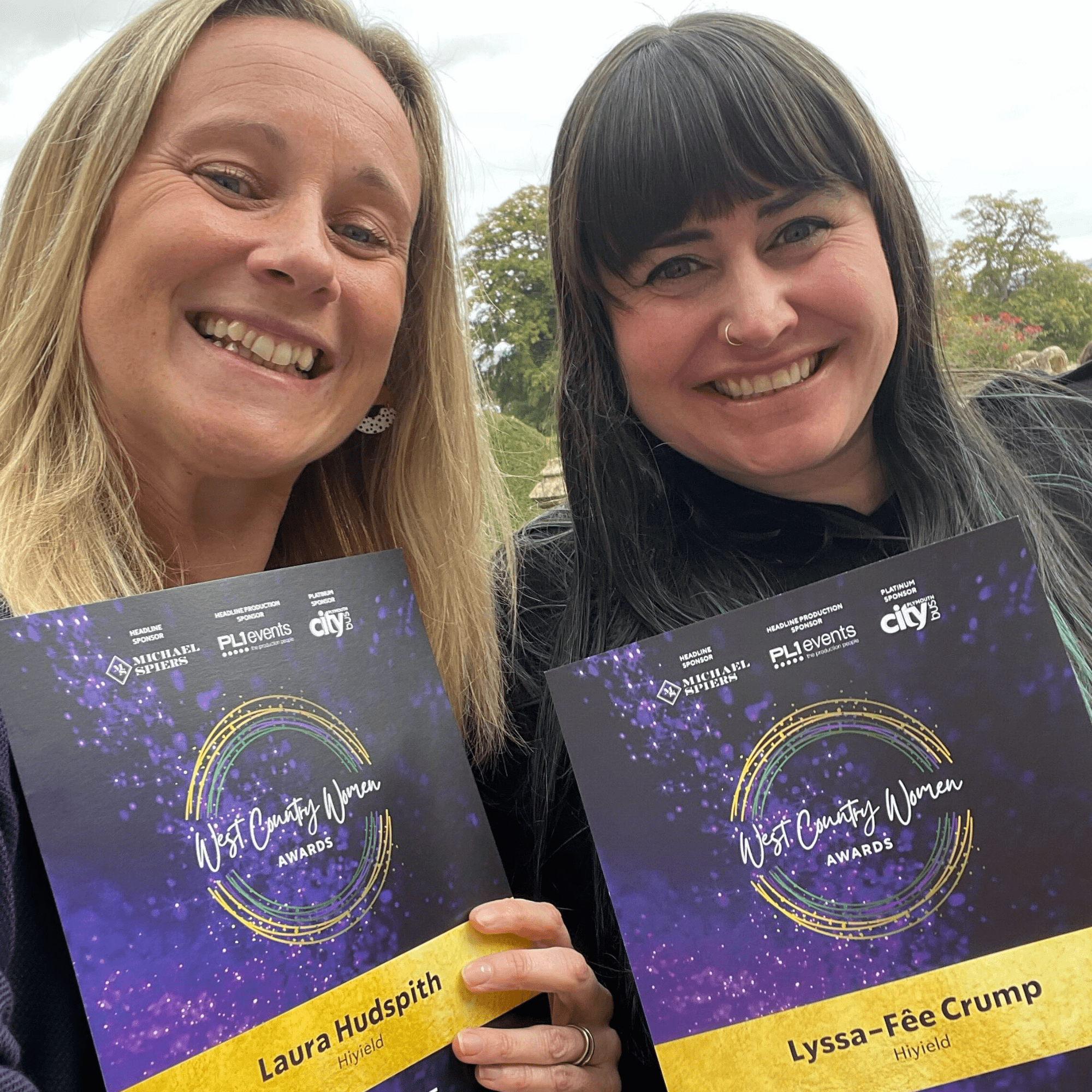 Laura Hudspith & Lyssa-Fêe Crump smiling and holding their West Country Women Awards finalist certificates.