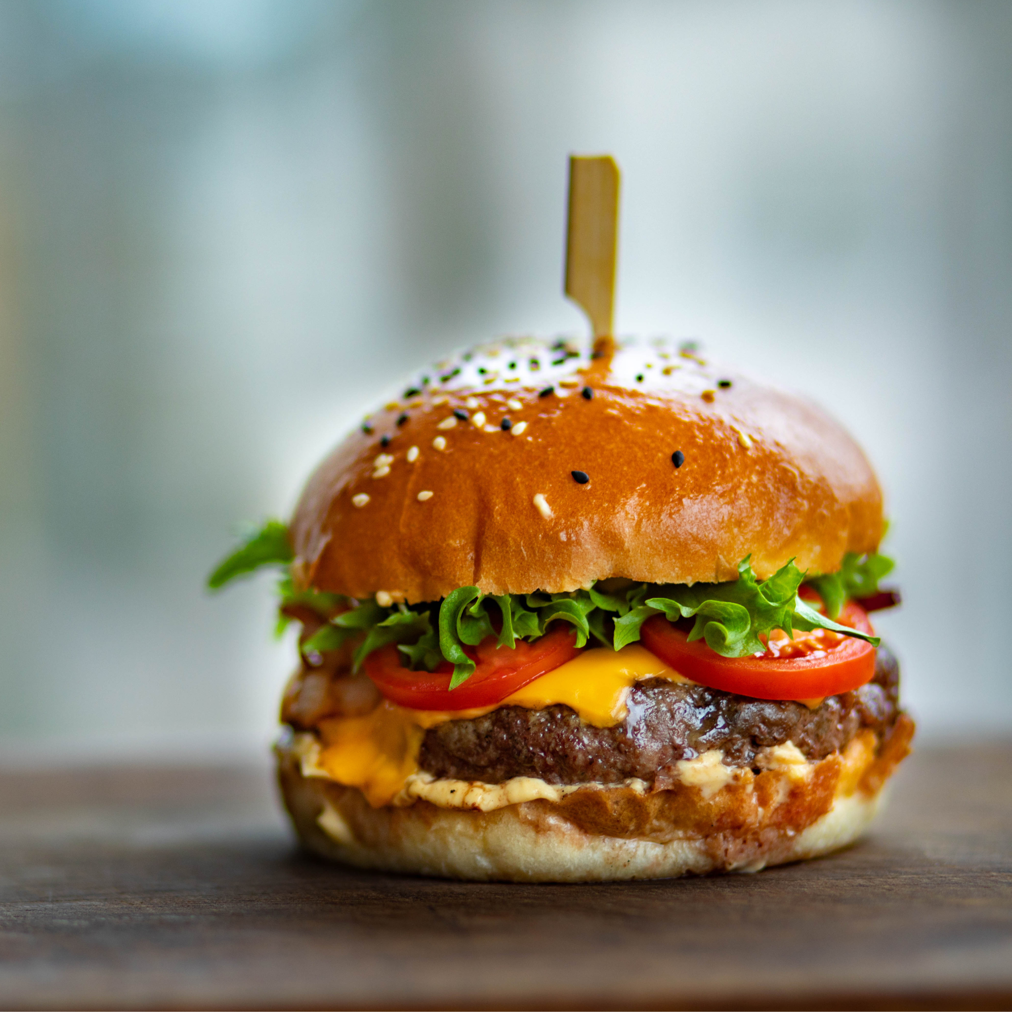 Juicy burger with sesame bun, cheese, tomato and lettuce.