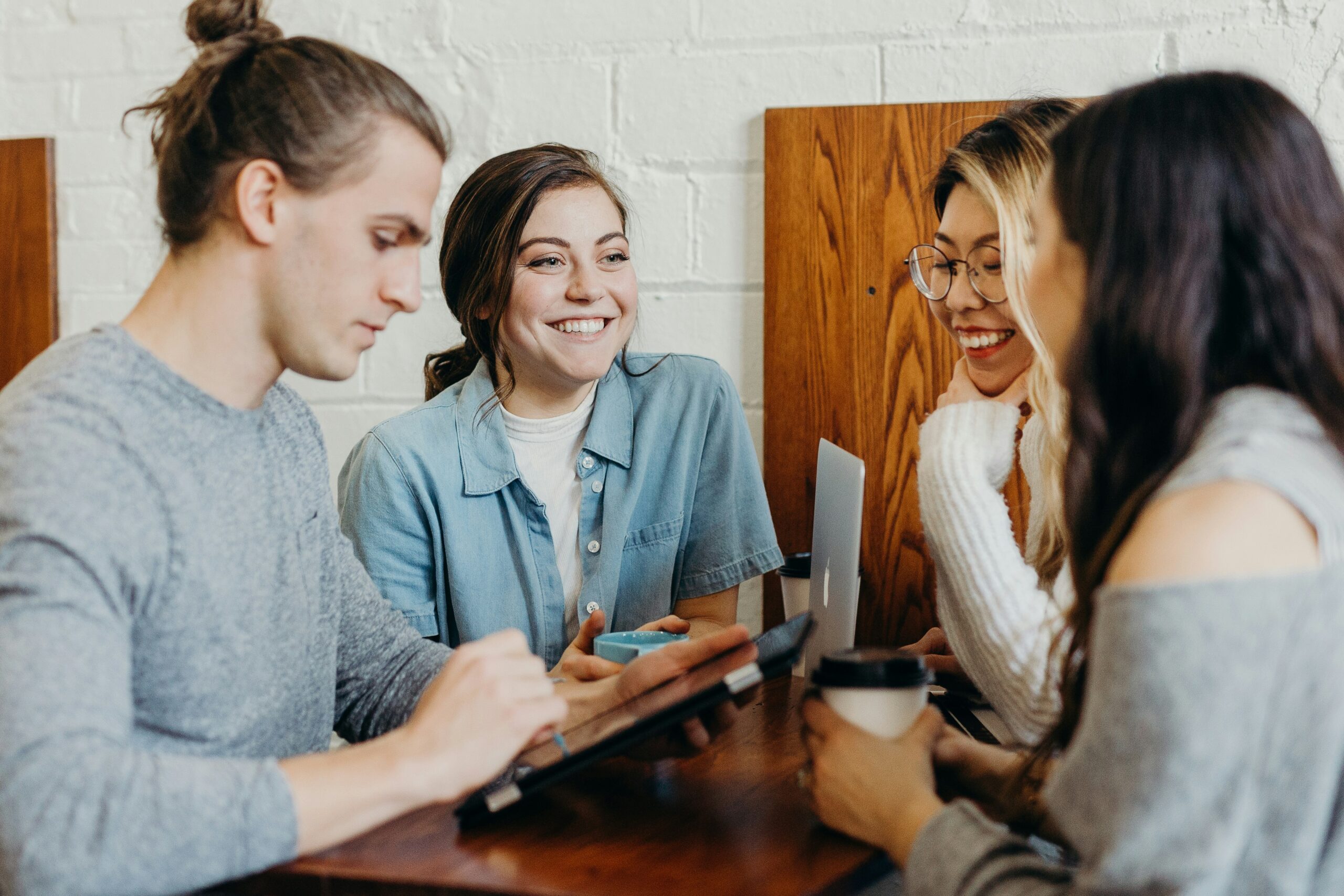 Three women and a man sat looking at a tablet discussing their startup.