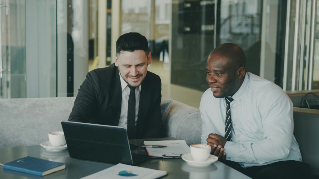 Two men in ties looking at an SEO audit on a laptop.