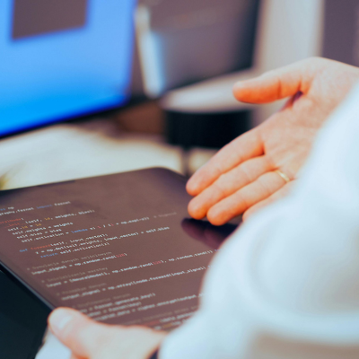 Hands over a tablet screen displaying code.