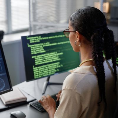 A woman sat at a computer coding.
