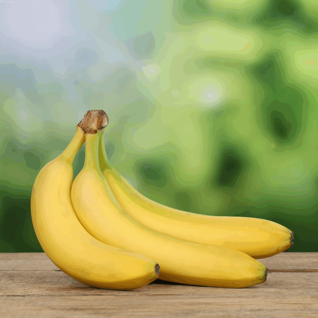 Bunch of bananas sat on a table, with green plants in the background.