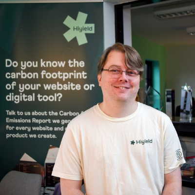 Ben from Hiyield in their Truro office, smiling next to the award shelf.